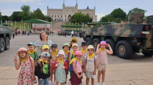 Dzieci na tle zamku i wozów wojskowych